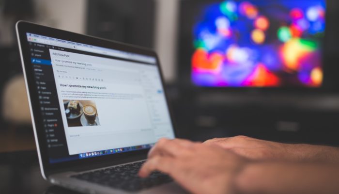SEO: o que é texto âncora e como usar no meu blog? Homem digita em notebook editando artigo de blog, representando o texto-âncora