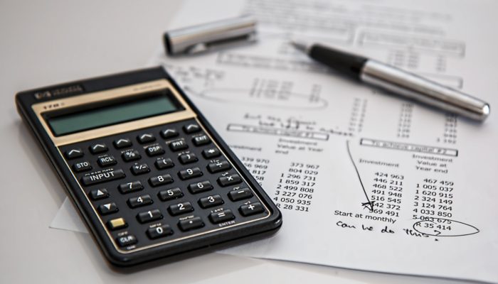 Saiba qual é o papel do contador em seu e-commerce Calculadora ao lado de caneta e papel com anotações numéricas representam o papel do contador