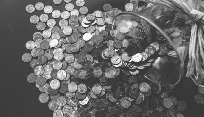 Pote de moedas virado na mesa representa o orçamento para loja virtual