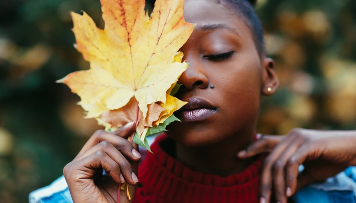 O que é e como aplicar a inteligência emocional no trabalho? Mulher com os olhos fechados e uma folha encostada no rosto, representando como desenvolver a inteligência emocional no trabalho