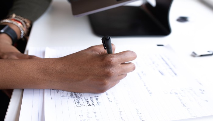 Mão escrevendo sobre papel, definindo entre os diferentes tipos de empresa