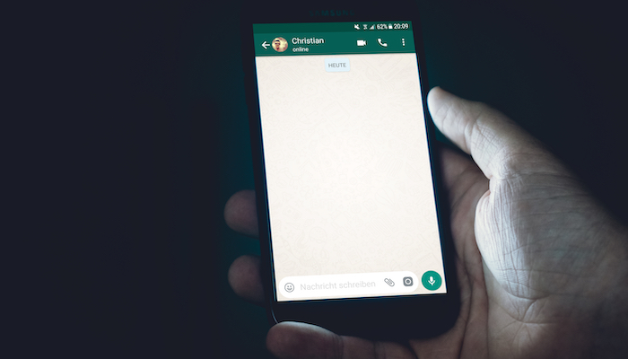 10 dicas de como vender pelo WhatsApp Mão segurando celular com o app do WhatsApp aberto, representando como vender pelo WhatsApp