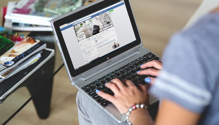 Imagem mostrando uma pessoa usando um notebook para uma página ou perfil d =o Facebook.