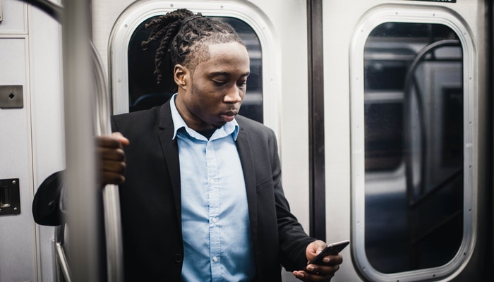 O que é PIX e como usar este meio de pagamento? Imagem mostrando um homem no metrô usando um celular, representando uma transferência bancária através do PIX.
