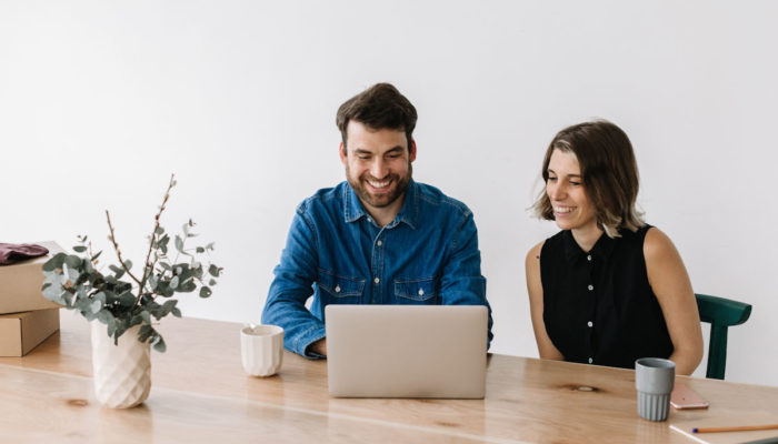 5 claves para crear la página “Quiénes somos” para tu empresa hombre y mujer sonrientes trabajando con laptop