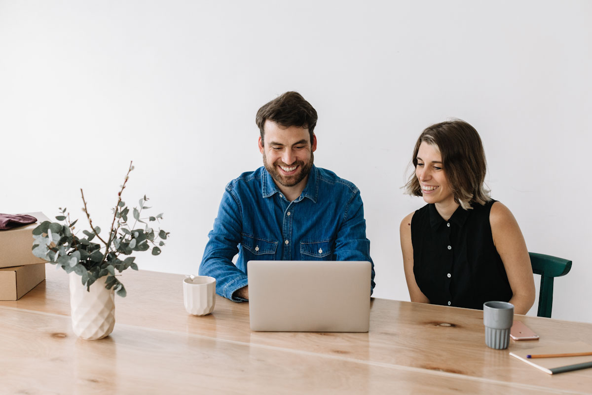 hombre y mujer sonrientes trabajando con laptop