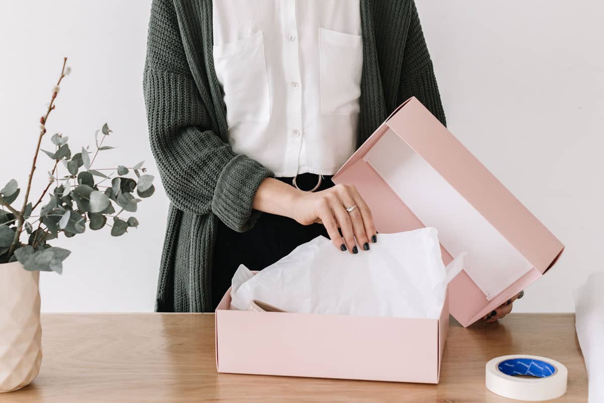 Mujer empacando un producto en una caja rosa