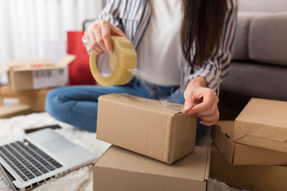 Mujer empacando producto en caja para envío