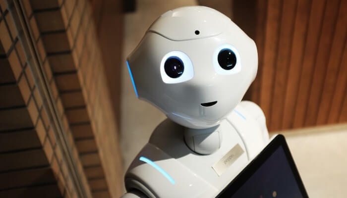 Robô branco com rosto segura um tablet, representando a automação de marketing