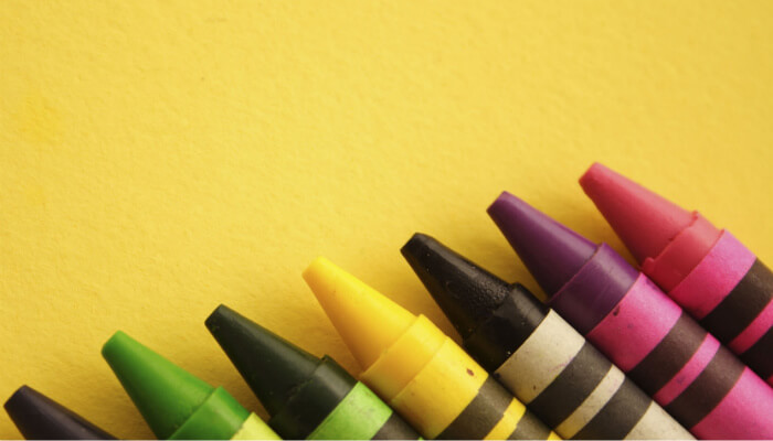 Cursos online grátis com as melhores práticas de design para a sua loja virtual Imagem de coleção de giz de cera coloridos sobre fundo amarelo, representando curso de design para layout de loja virtual
