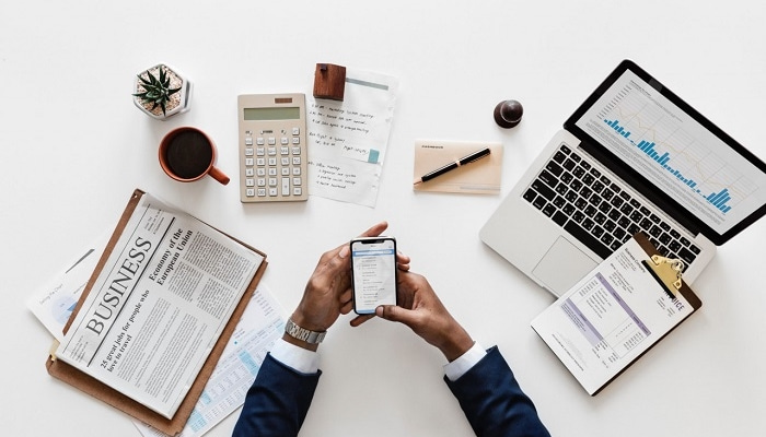 O que é e-commerce B2B e como ele se diferencia do B2C? Empreendedor sobre mesa com notebook, jornal e caderno representa o e-commerce b2b