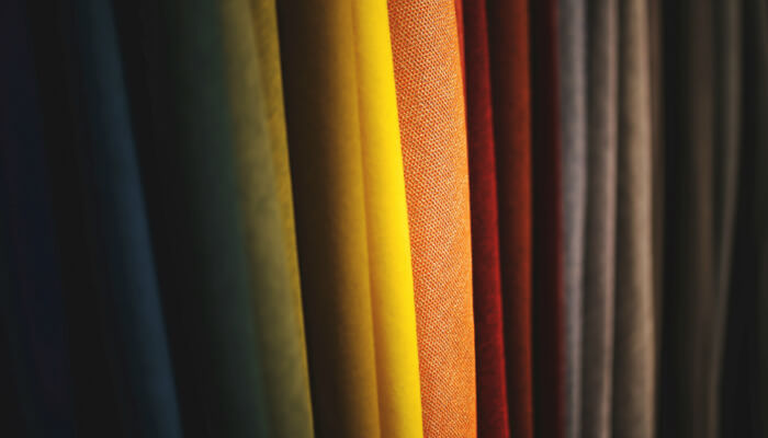 Tecidos coloridos enfileirados, representando qual o melhor tipo de tecido para camiseta