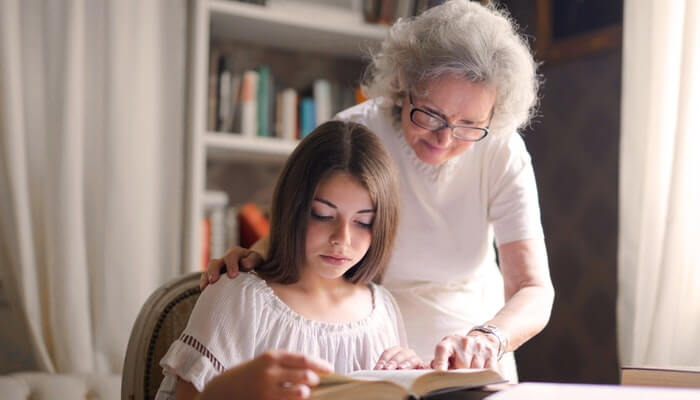 Duas mulheres, uma jovem e uma idosa, leem o mesmo livro interessadas, apreciando o storytelling