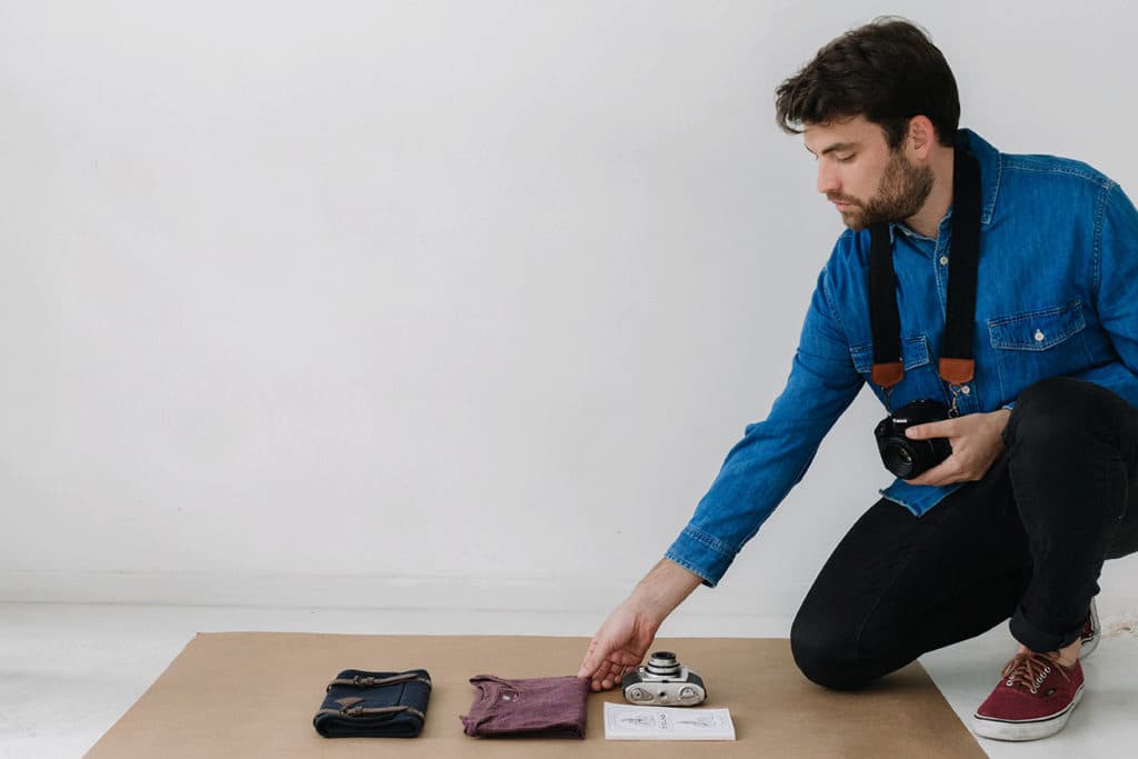 Hombre acomodando prendas sobre un papel kraft para tomar fotografía de producto