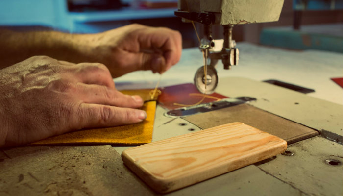 Por que vender artesanatos online é uma ótima ideia? Mãos costuram em frente à máquina de corte, representando vender artesanato online