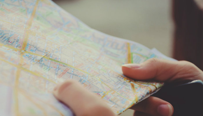 Como direcionar o seu negócio através de metas e planos de ação Mãos segurando mapa representam como elaborar um plano de ação