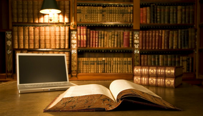 O crescimento do e-commerce e a importância de estar regularizado Livro e computador em mesa de biblioteca representam o jurídico no e-commerce
