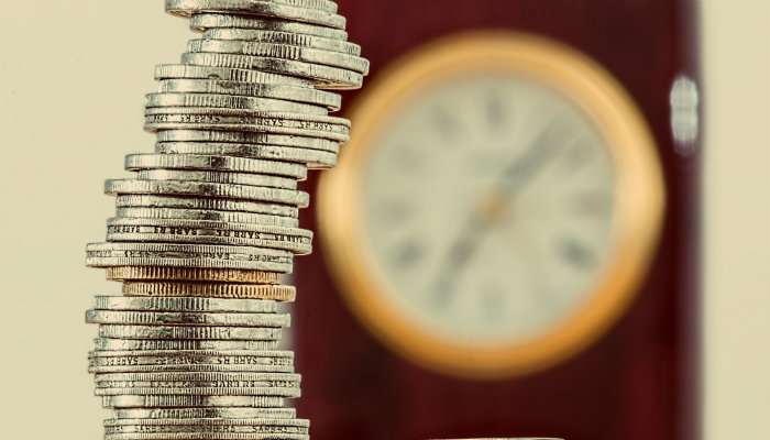 Como descobrir se é a hora certa para lançar um novo produto Pilha de moedas em frente a relógio, representando quando e como lançar um produto no mercado