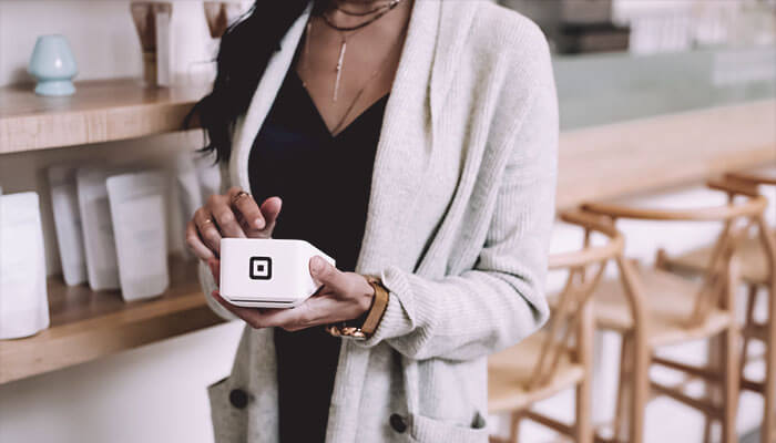 O que são e como funcionam os meios de pagamento online? Mulher passa cartão em máquina, representando os meios de pagamento