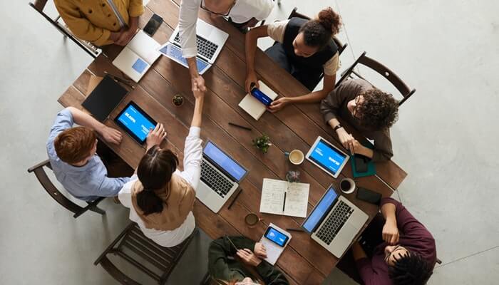 Como fazer pesquisa de satisfação do cliente com o Survey Monkey Mesa com pessoas fazendo reunião vista de cima representa a pesquisa de satisfação do cliente