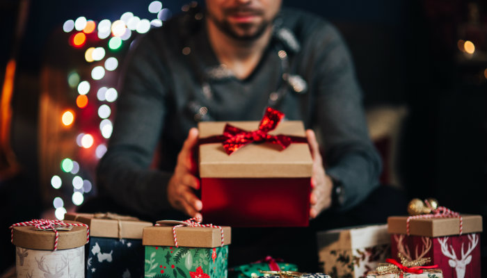 Ideias de presentes masculinos para o seu Amigo Secreto de Natal Homem segura embrulho representando os presentes masculinos