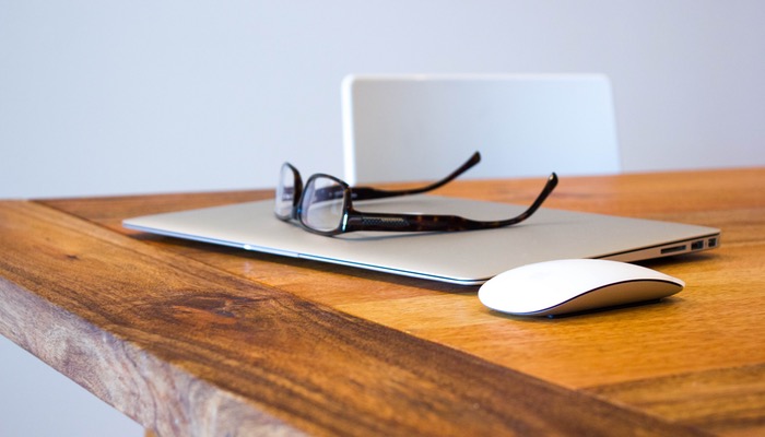 Como ser produtivo trabalhando durante uma viagem como nômade digital Notebook fechado sobre mesa com óculos em cima representa a produtividade em viagem