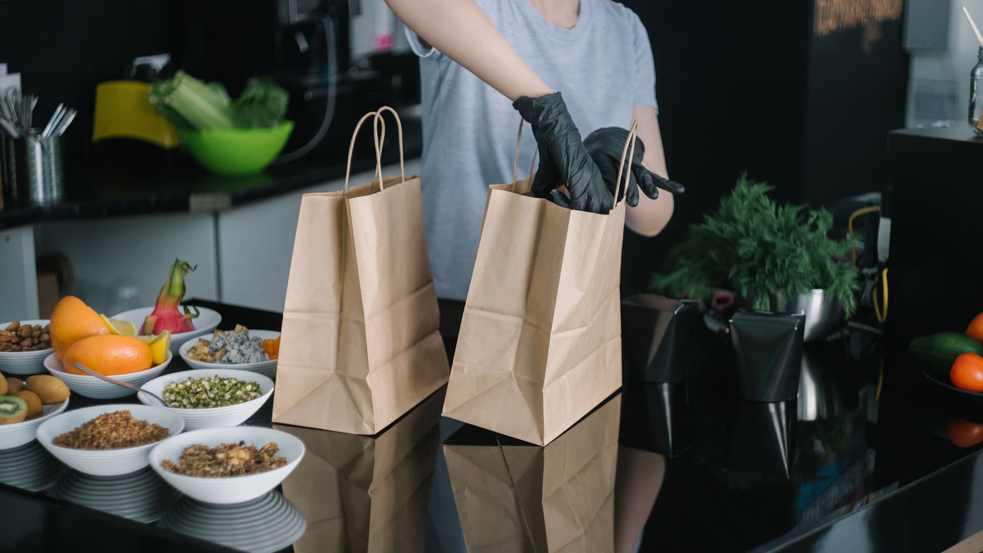 Persona con guates guardando comida para llevar en bolsa de cartón