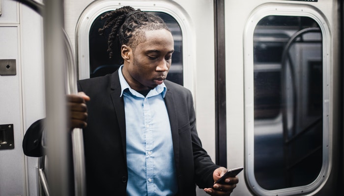 Imagem mostrando um homem no metrô usando um celular, representando uma transferência bancária através do Pix.