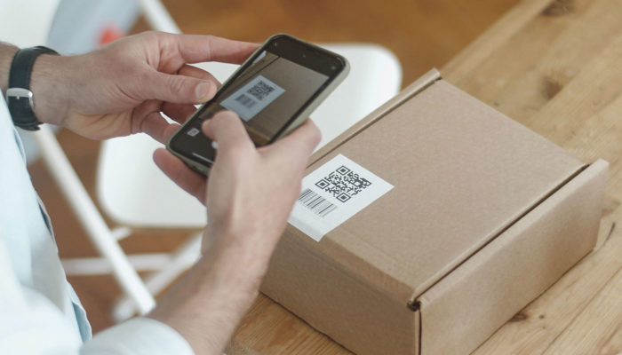¿Qué es un código de barras y cómo hacer uno? persona escaneando una etiqueta con código de barras y código QR con un smartphone