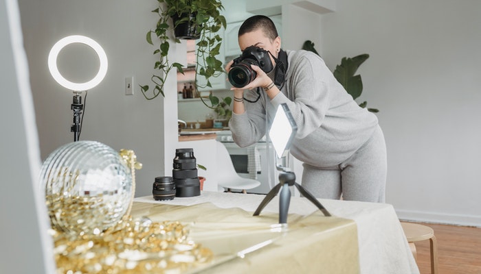 Como tirar fotos de produtos para sua loja virtual e aumentar suas vendas? Imagem mostrando uma mulher tirando boas fotos de produtos para e-commerce.