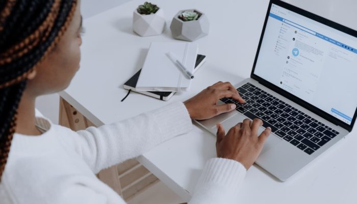 Cómo abrir una cuenta de Facebook para tu negocio: tutorial paso a paso Mujer abre su cuenta de facebook en laptop mesa blanca con dos plantas pequeñas