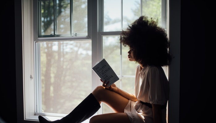 Imagem mostrando uma mulher lendo livros para empreendedores.
