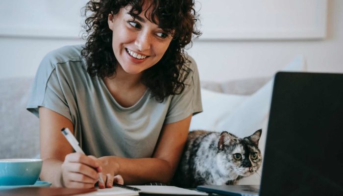 mujer tomando curso de ecommerce frente a su laptop junto a su gato