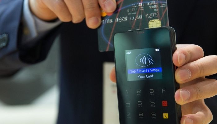 cartão de crédito em máquina passando em uma máquina de cartão de crédito, ilustrando um exemplo de arranjo de pagamentos