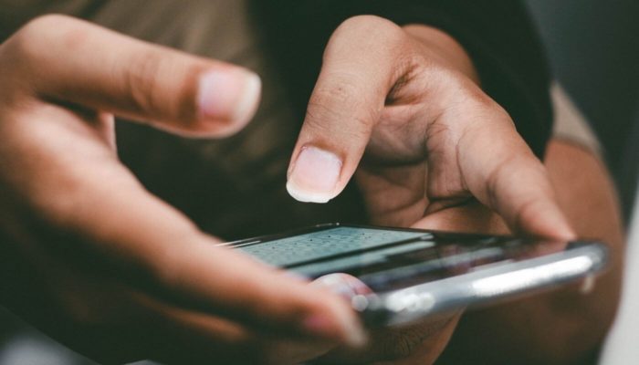 O que é e como criar um chatbot? mulher respondendo interação de chatbot em um celular