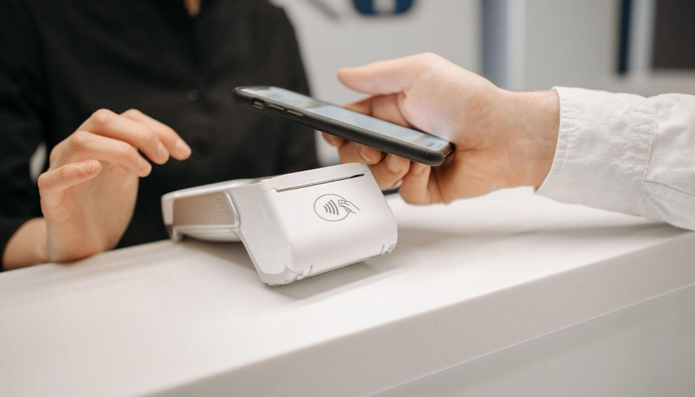 celular conectando com máquina de cartão de crédito, o que representa o estorno de pagamento feito por compras com cartão de débito