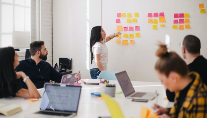 15 estratégias de marketing digital para promover o seu negócio mulher apresentando as estratégias de marketing digital em reunião de equipe
