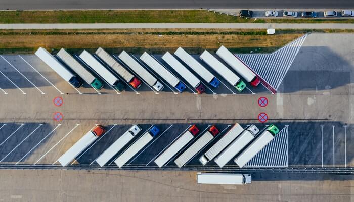 Imagem aérea de caminhões estacionados em pátio representa a gestão de frotas