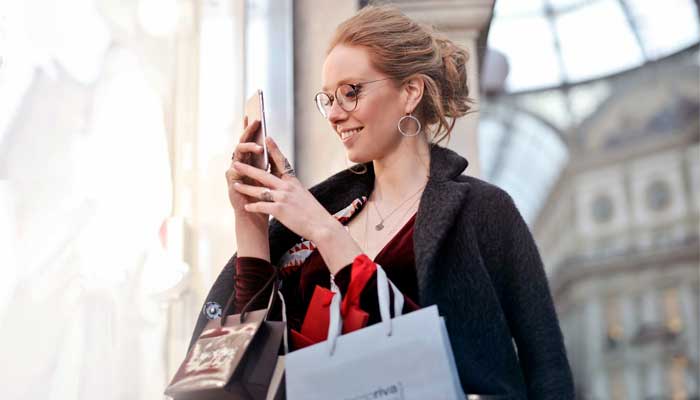 Consumidora com sacolas nas mãos recebe e-mail de campanha de mobile marketing