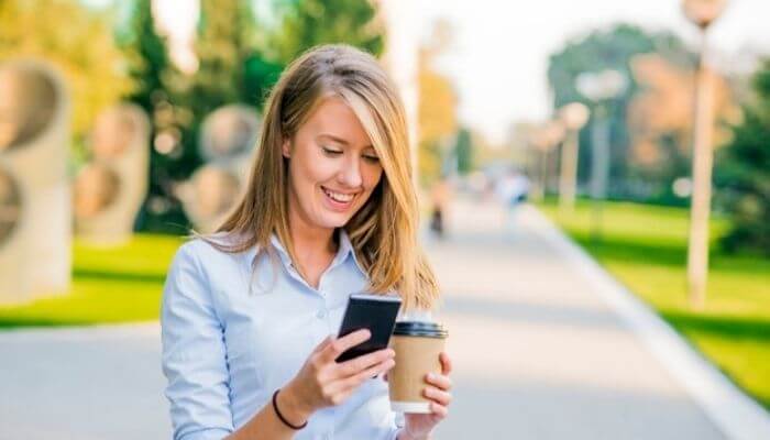 mulher confiante se informando pelo celular, o que representa uma das premissas do marketing 4.0
