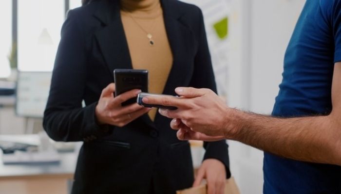 imagem mostra duas pessoas com celulares em mãos, ilustrando uma transação de pagamento instantâneo