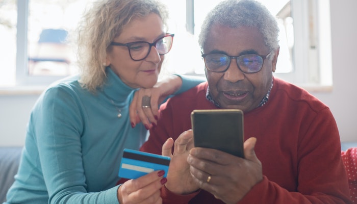 Imagem mostrando duas pessoas usando um cartão de crédito em uma compra online, representando o pagamento parcelado.