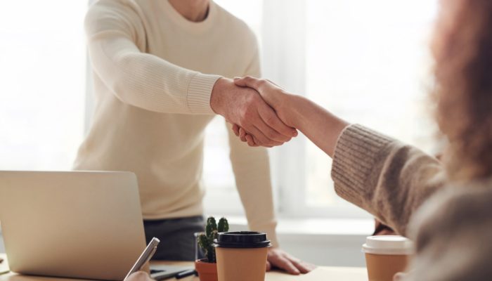 Como fazer parcerias com lojas virtuais? Na imagem, vemos duas pessoas de mãos dadas comemorando parcerias com lojas virtuais