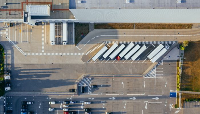 Vista aérea de centro de distribuição com caminhões estacionados representa o planejamento logístico