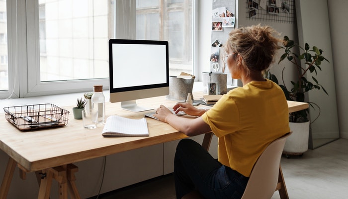 Imagem mostrando uma mulher em frente a um laptop, representando como usar o TikTok no PC.