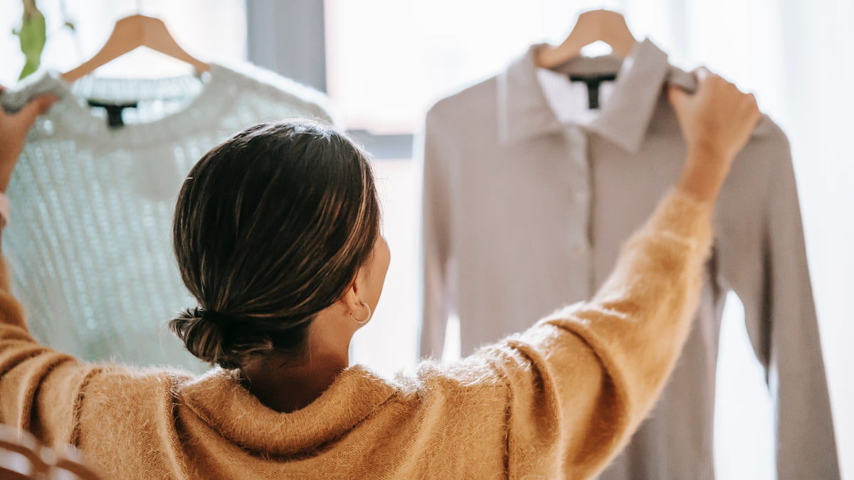 Mujer dando la espalda comparando dos prendas de ropa - errores al vender ropa en linea