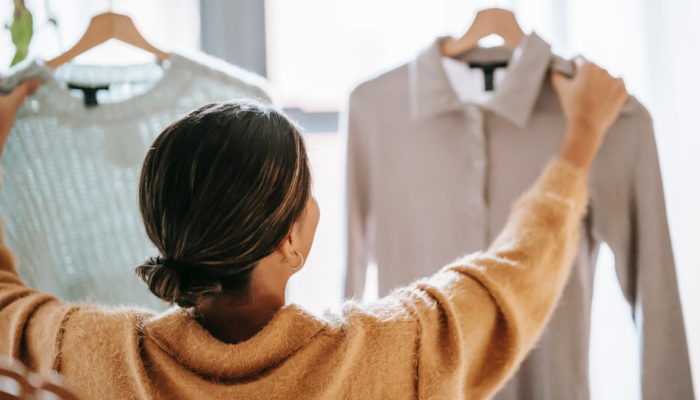 Mujer dando la espalda comparando dos prendas de ropa - errores al vender ropa en linea