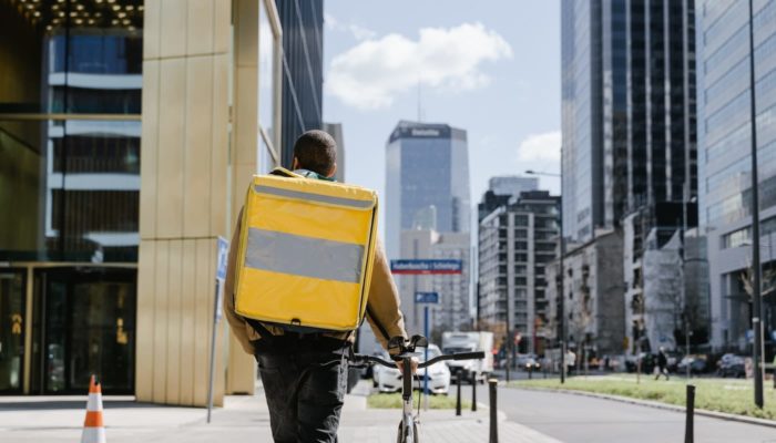 O que é logística sustentável e como aplicá-la no e-commerce? Homem com mochila de entrega e bicicleta representa a logística sustentável