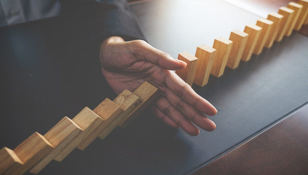 Imagem mostrando uma mão impedindo as peças de dominó de caírem ilustrando a importância de todas etapas do processo de vendas