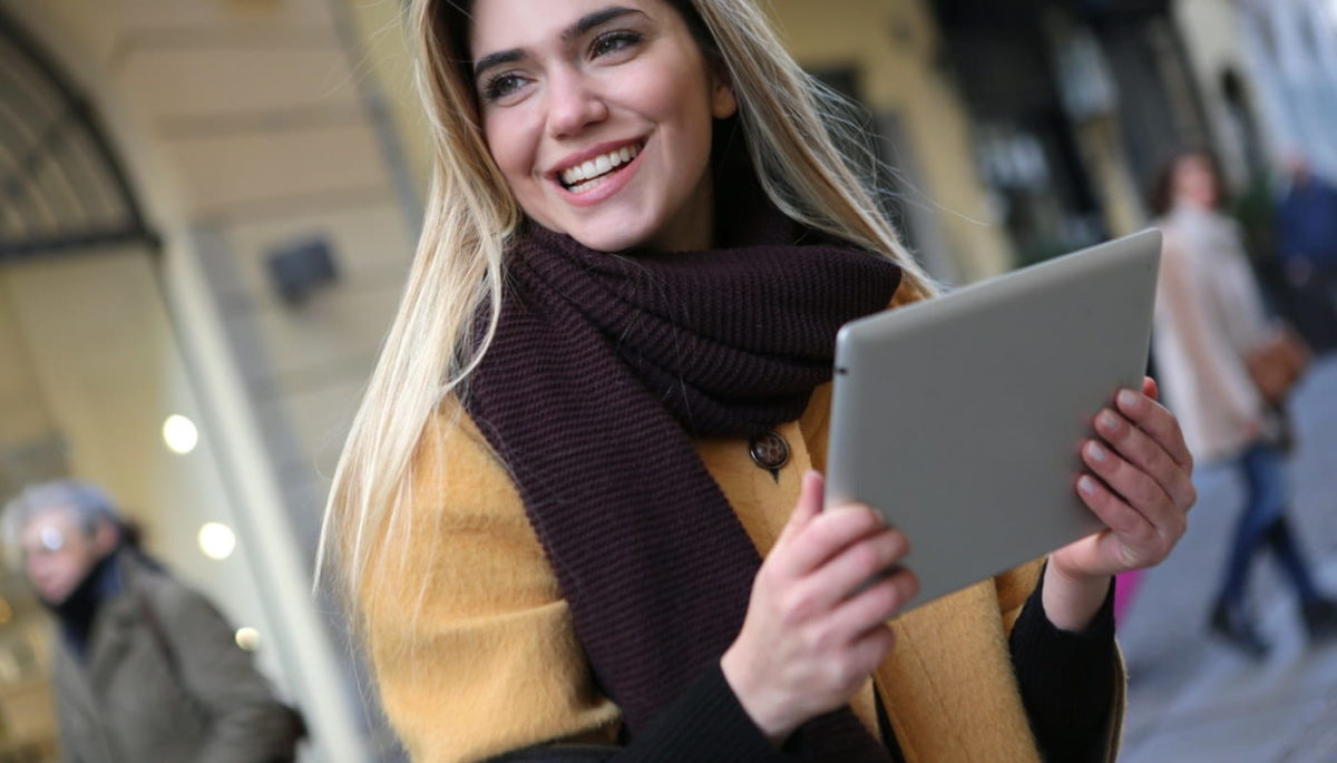 Imagem mostrando uma mulher sorrindo com um tablet na mão, representando o marketing de experiência.